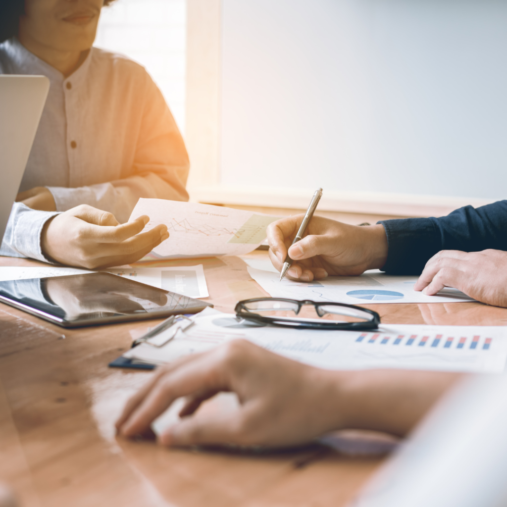 A team of professionals working around a table together, looking at graphs