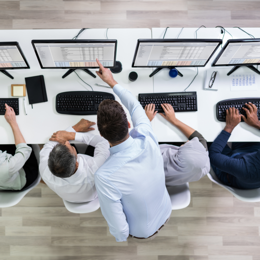 Someone training staff in a row all on their computers, all looking at the same screen of information. 