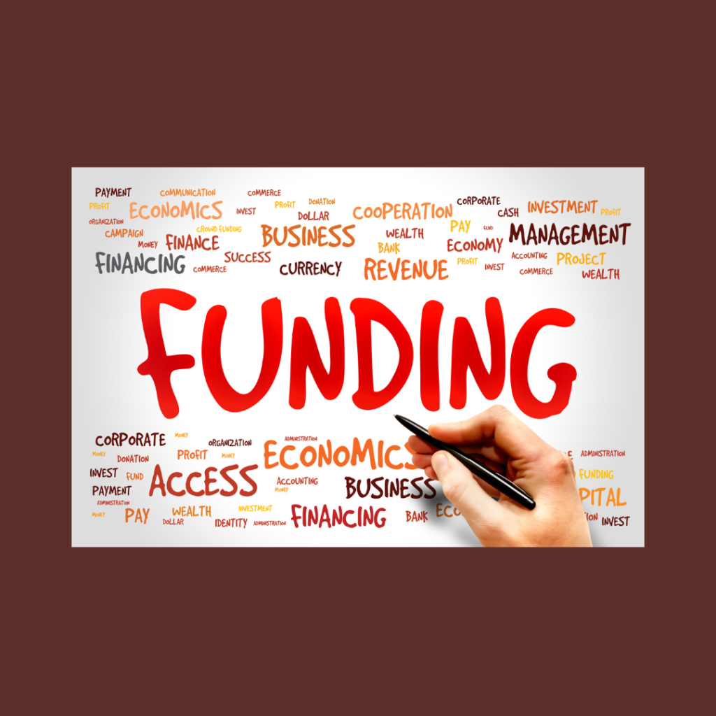 The word FUNDING front and centre with other financial words scattered around and a pen-poised-in-hand hovering in the foreground