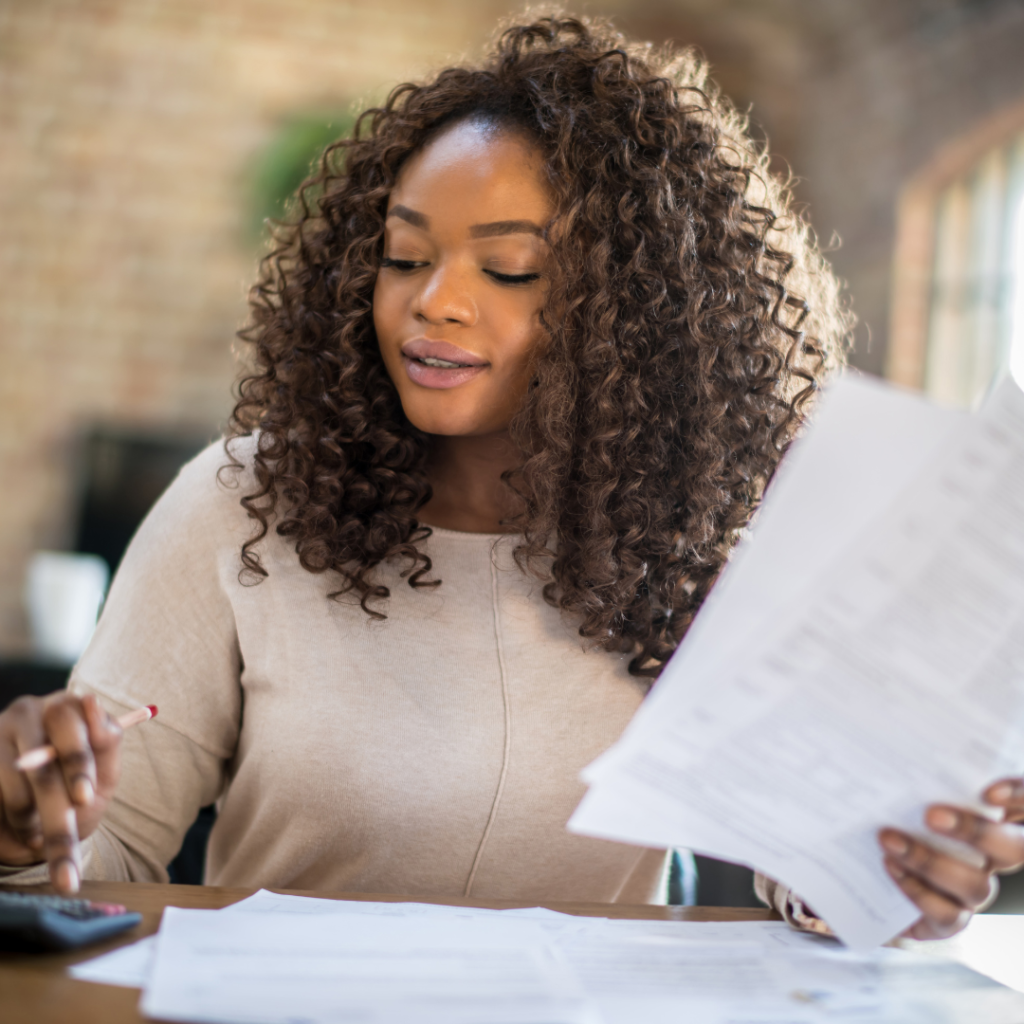 A woman crunching numbers while holding papers in her left hand 